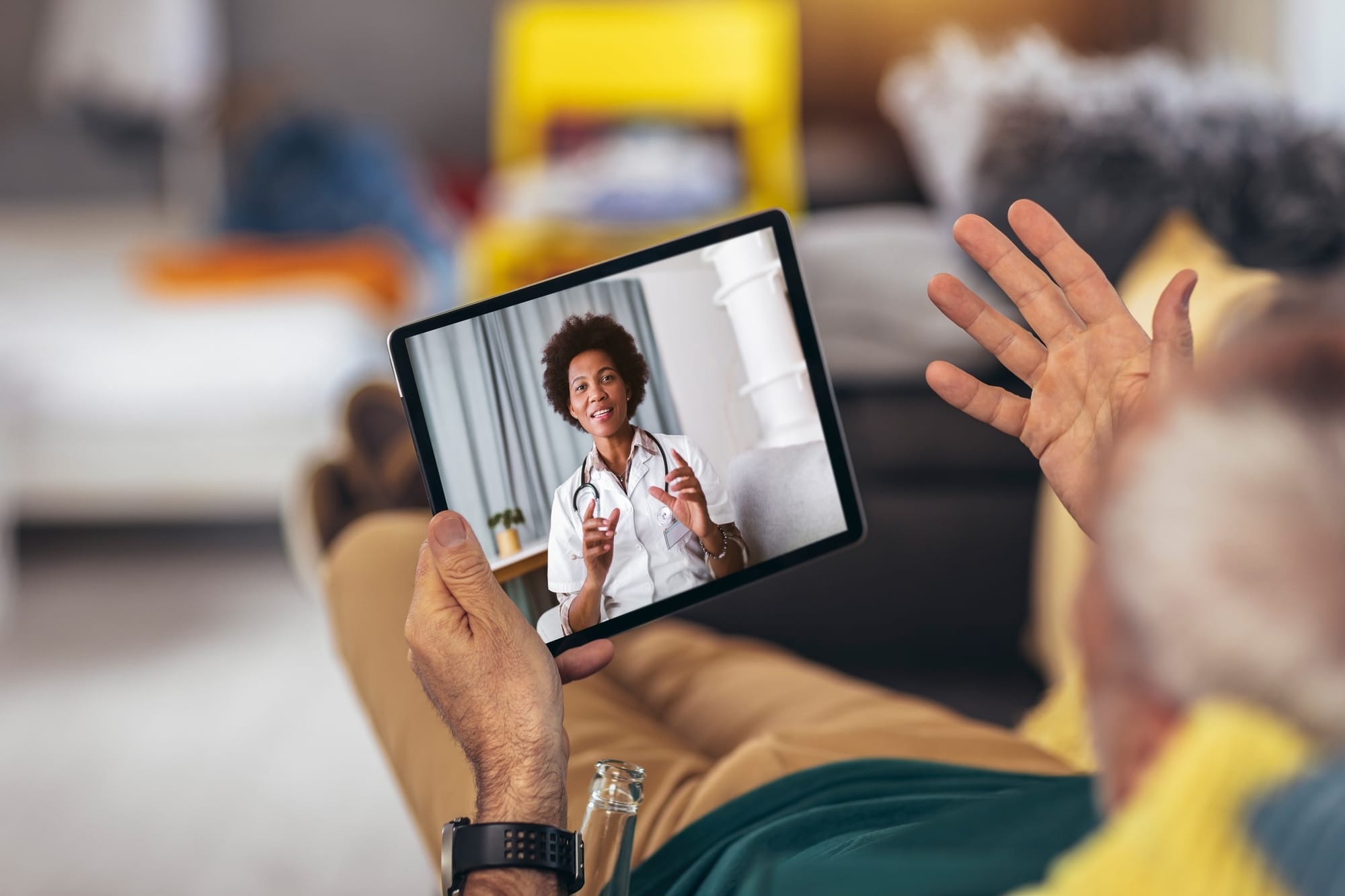 Man makes a video call to his medical consultant on digital tablet at home.