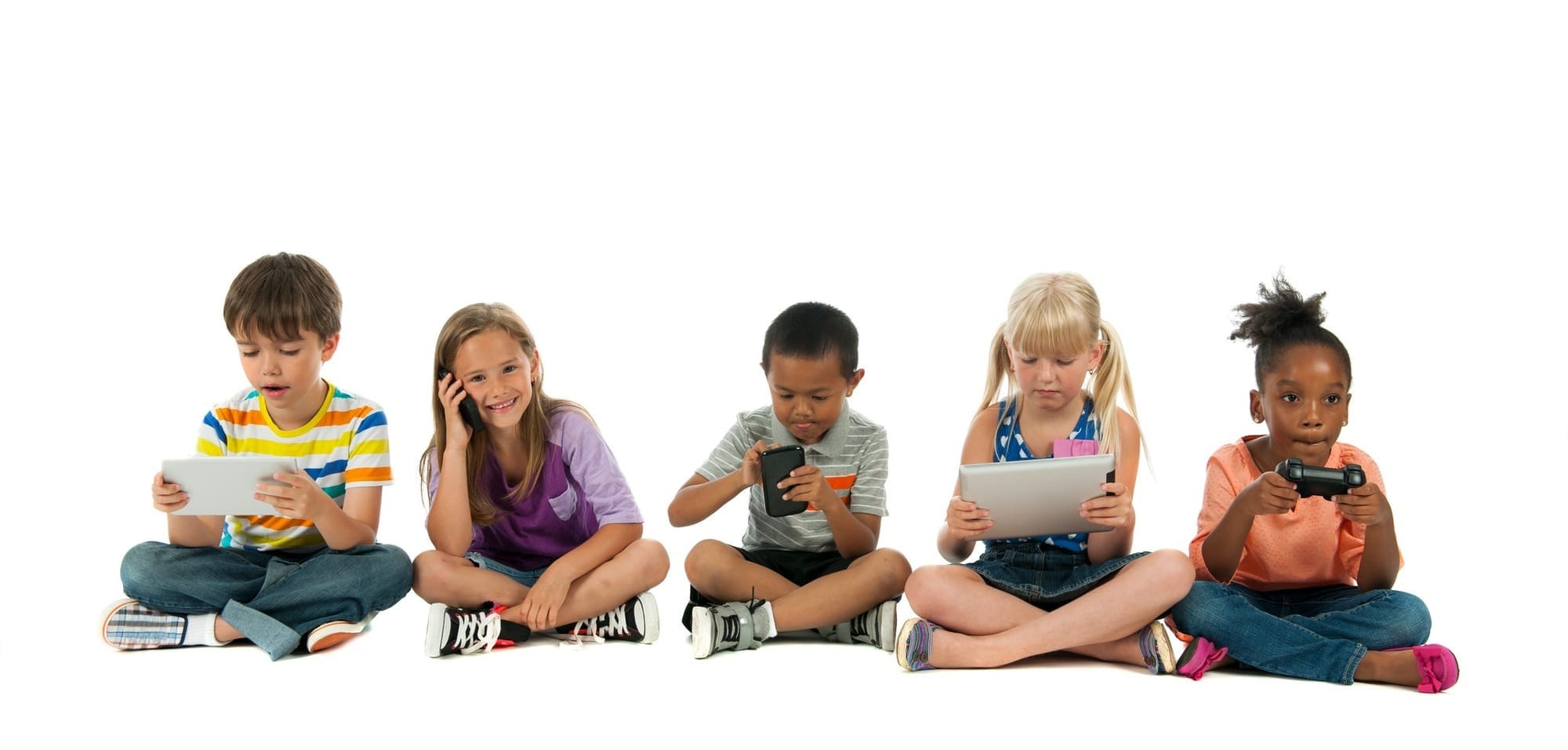 A diverse group of children sitting cross-legged with a variety of hand held devices.