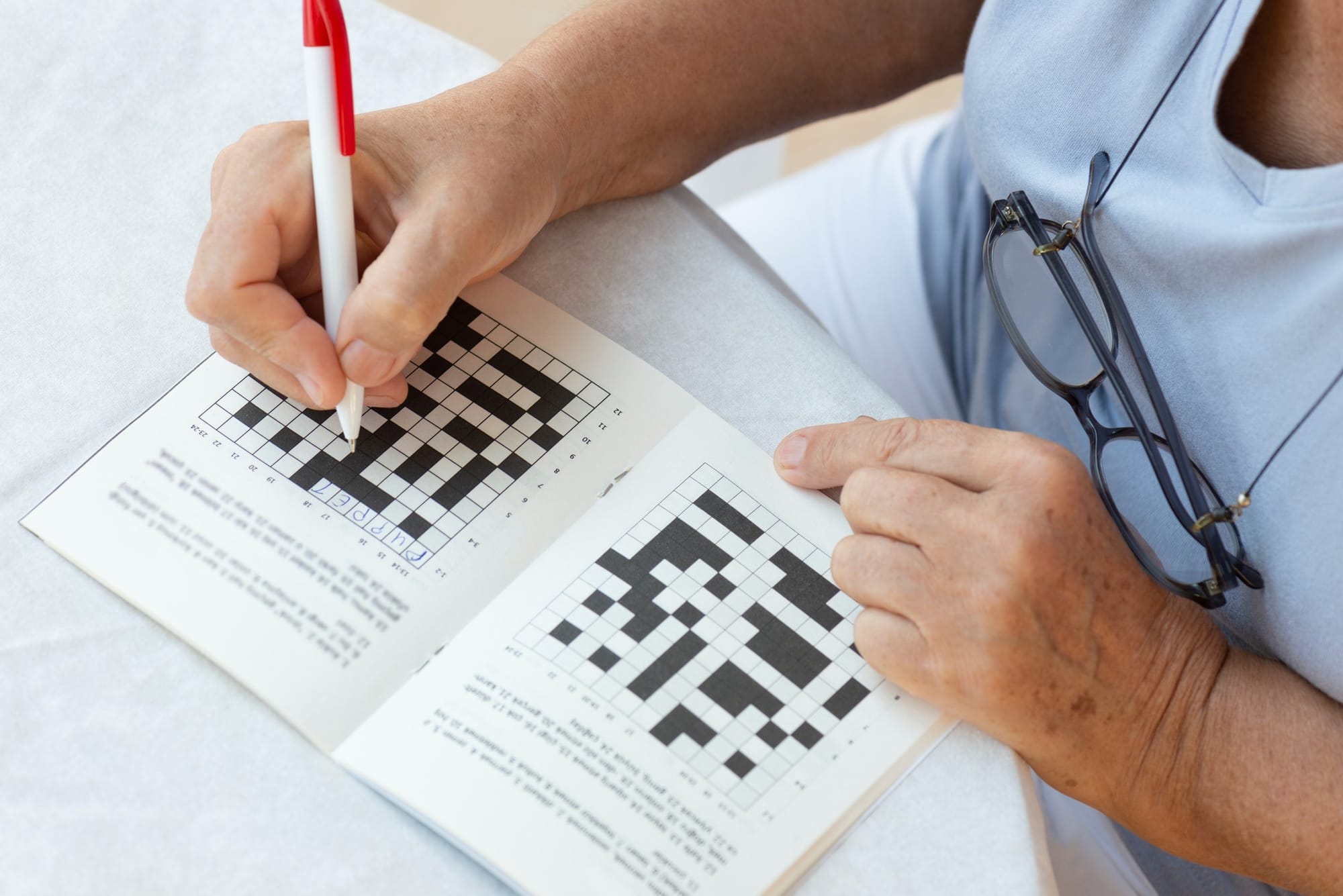 Women with a pen in her hand doing a crossword.