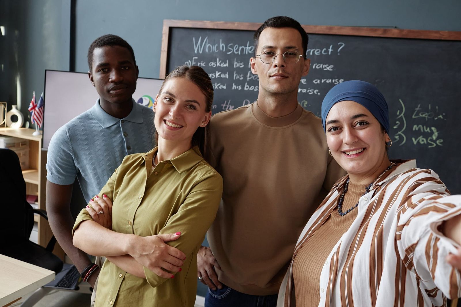 Group of teachers from multicultural backgrounds in front of a blackboard in a classroom.