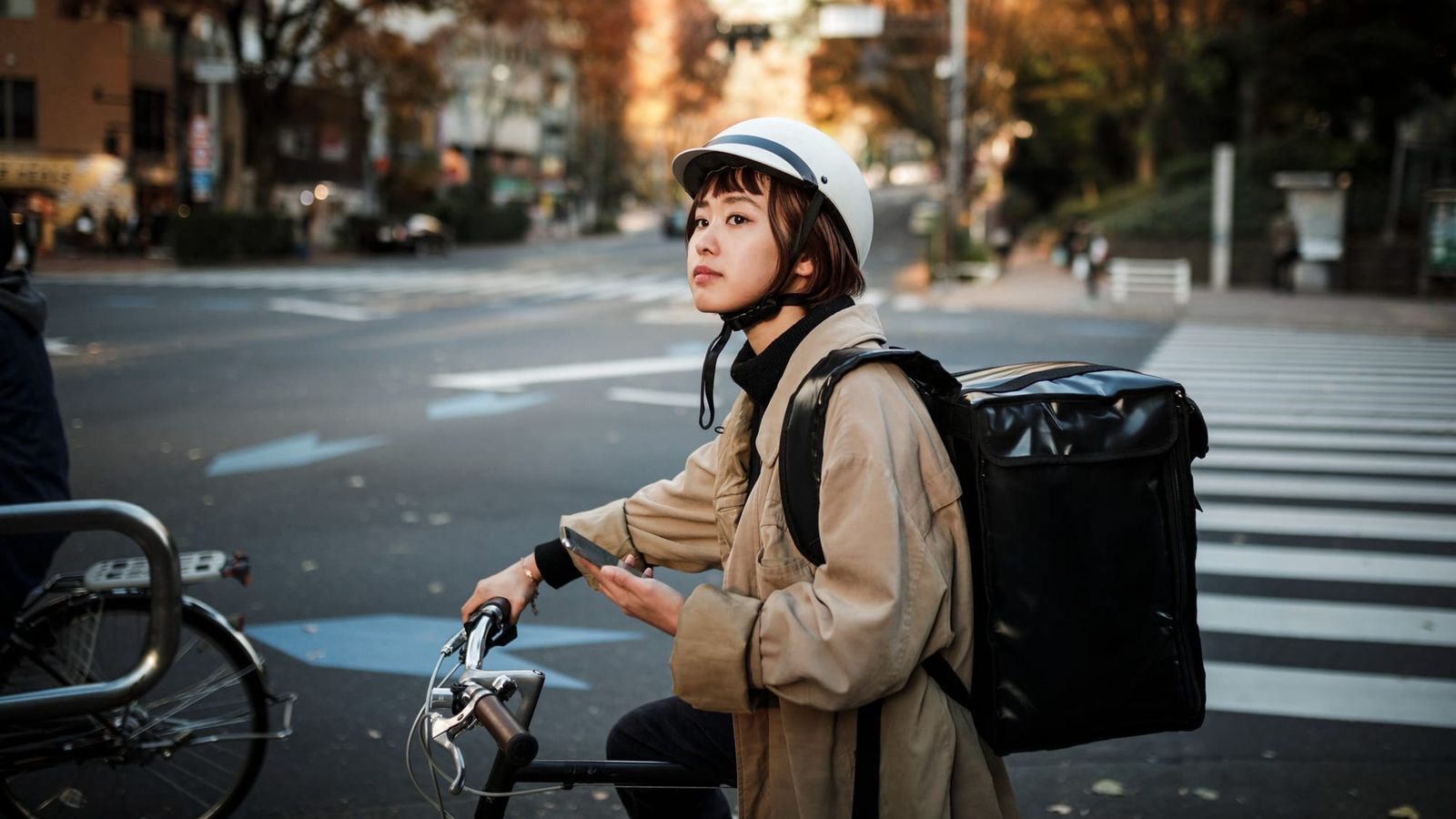 Young woman riding a bike with delivery bag, working for a food delivery app.