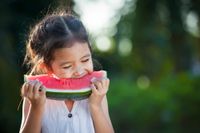 Happy young girl eating watermelon