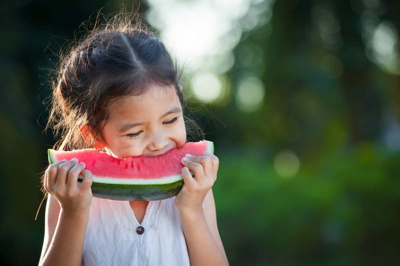 Happy young girl eating watermelon