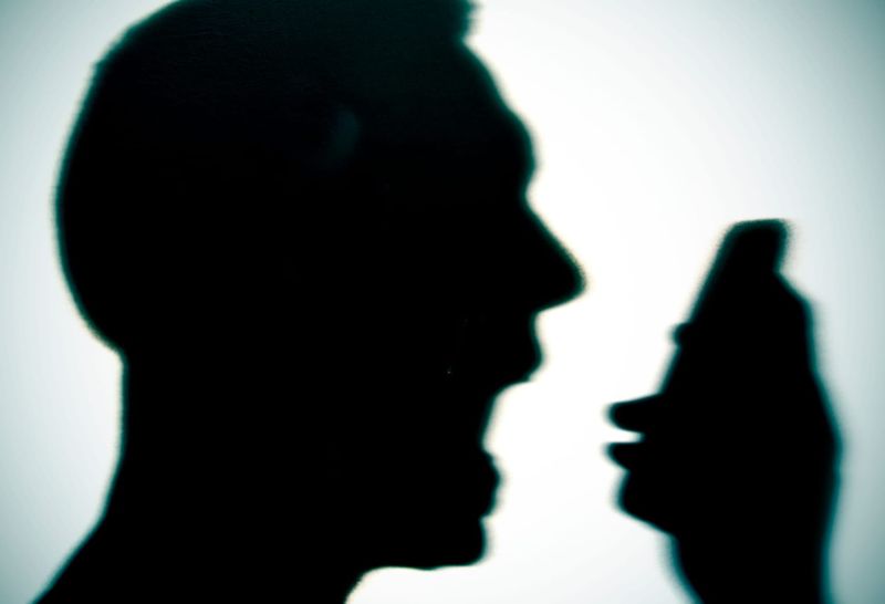 Closeup of the silhouette of a young man yelling into his phone