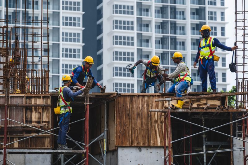 Construction workers wearing safety protective equipment while working on high-rise buildings at a construction site in Kuala Lumpur