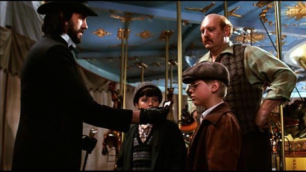 Carnival man in black offers a ticket to a boy beside a carousel as another boy and a shopkeeper watch - scene from a 1983 Disney film.