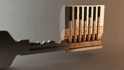 A brass lock mechanism with a key partially inserted, showing the internal pins and cylinder components that must align for the lock to open.