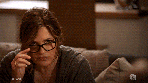A woman in glasses peers skeptically over her frames in an NBC SVU clip, conveying doubt about AI transparency claims.