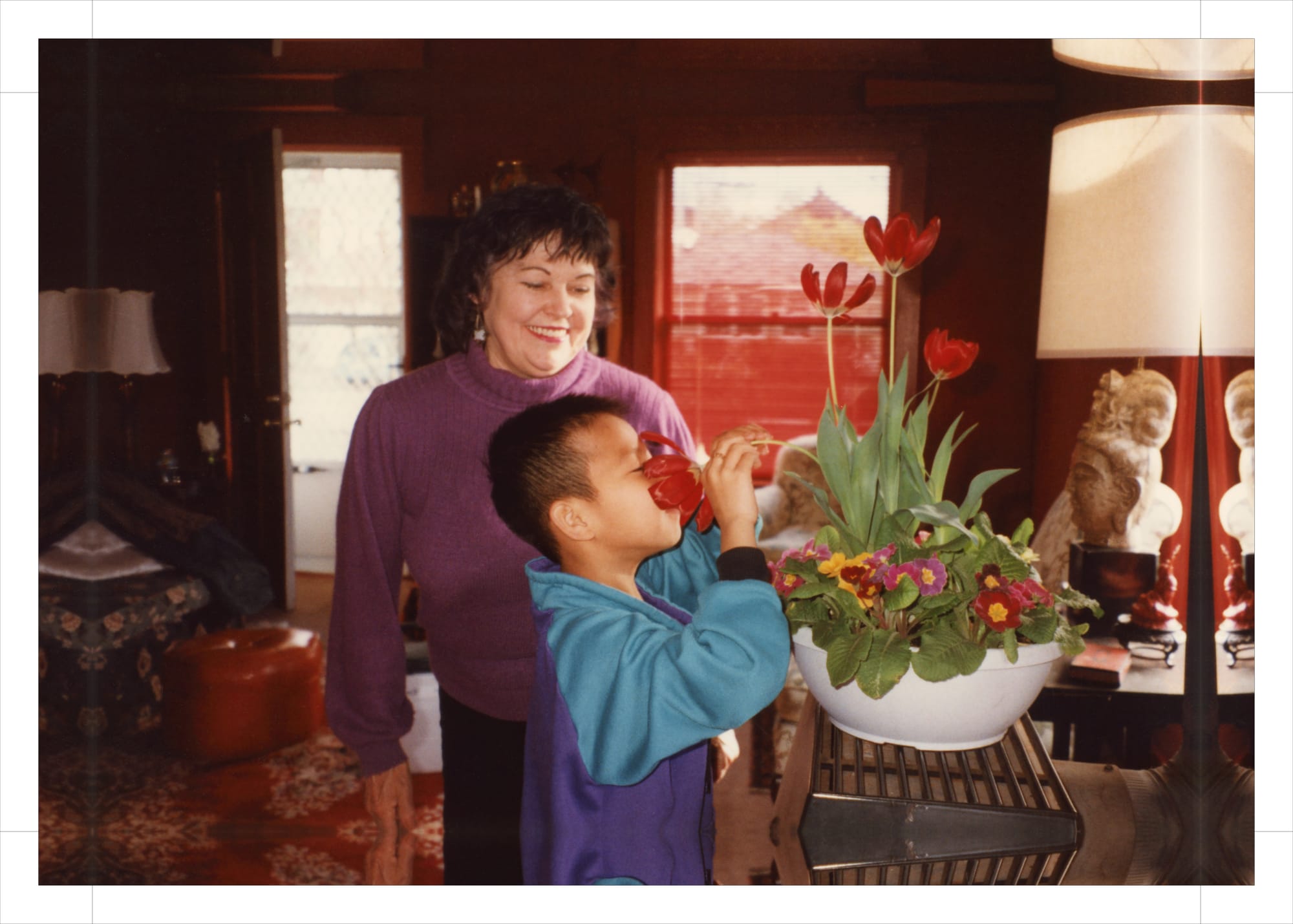 My grandmother watching me smell a Tulip.
