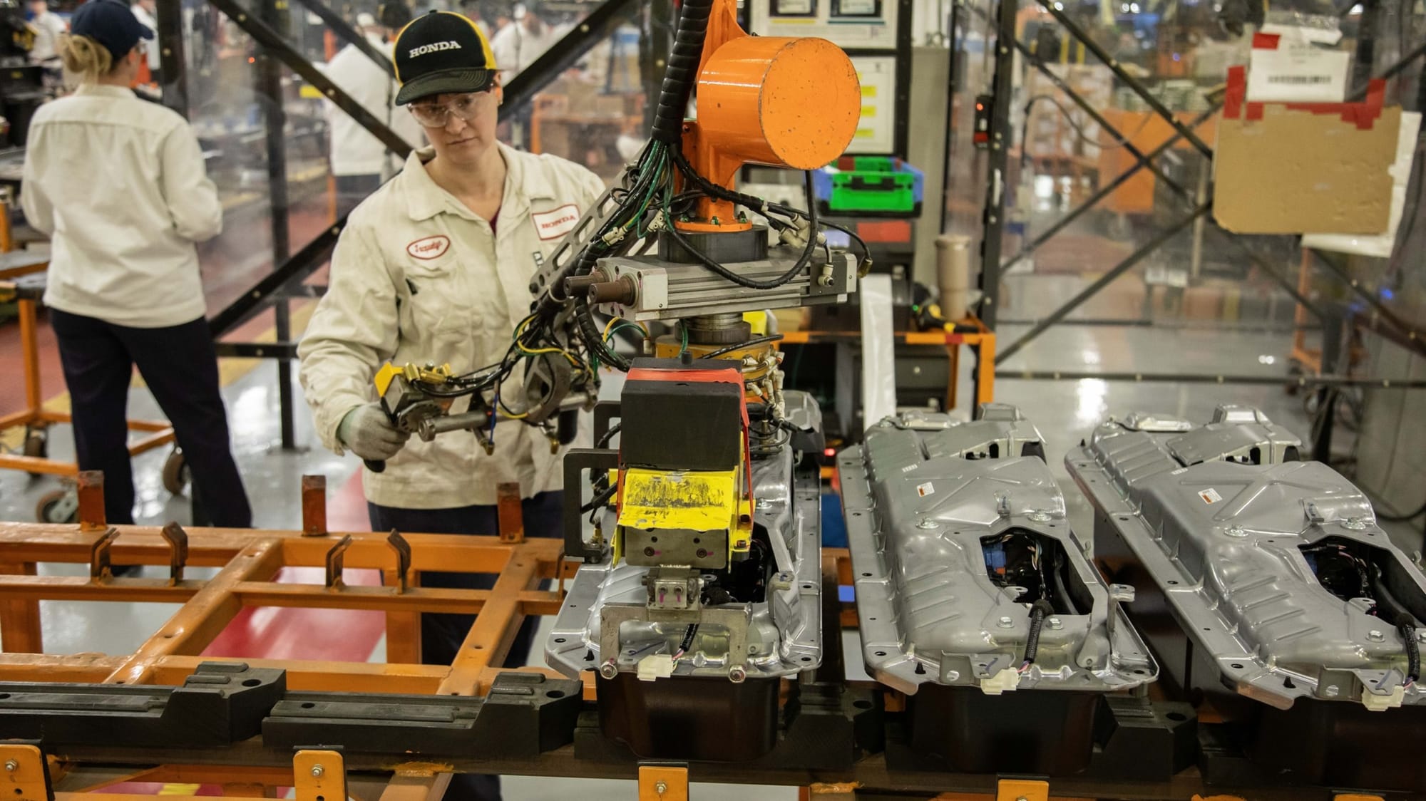 Assembly line worker pulling a fuel tank assembly at a Honda production plant.