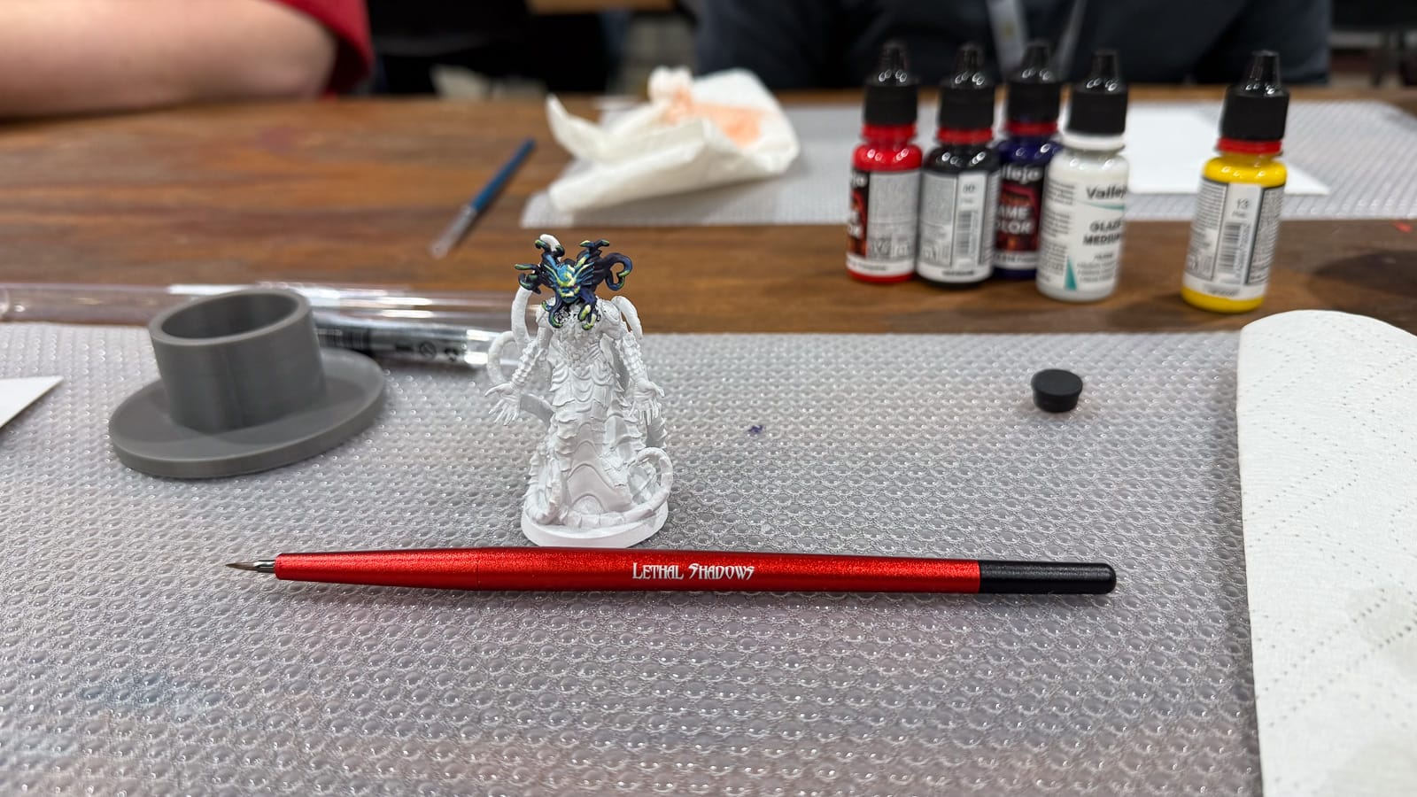 A photo of the Lethal Shadows Paint Scythe and a model with a painted face