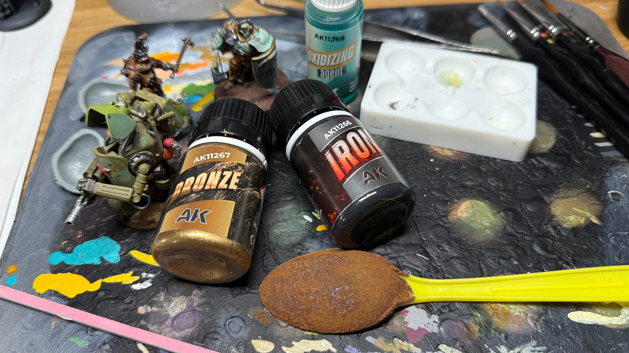 A photo of the AK Interactive Bronze effects and AK Interactive Rust effects on a work table along with models