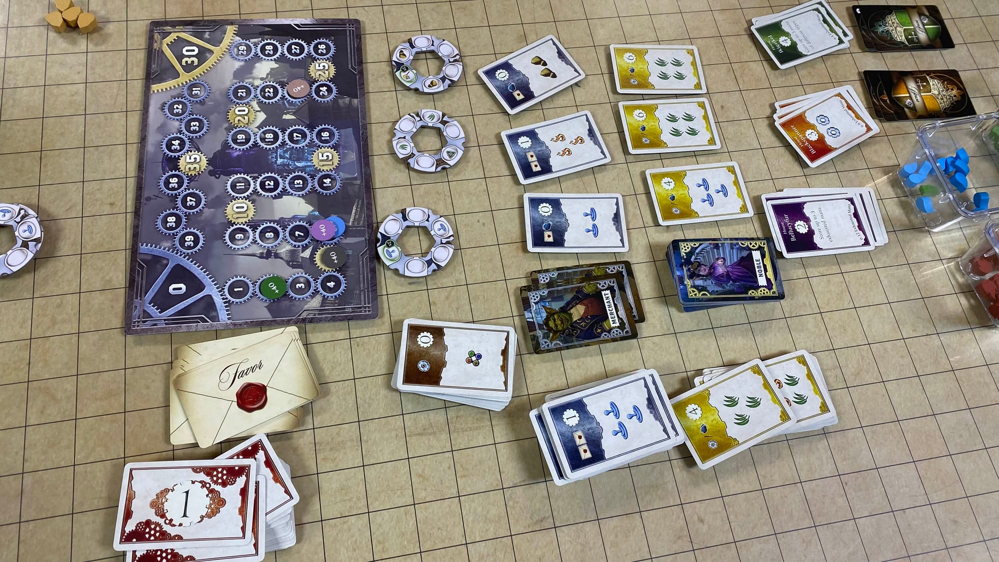 The common area: going left to right, there's the score track and favor deck, enchantments and commoner contracts, merchant contracts, noble contracts, and finally house petition cards.