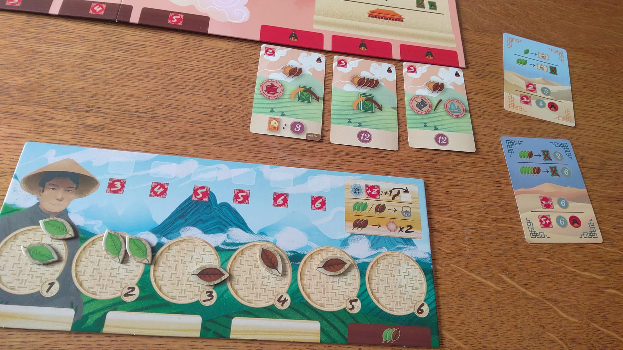 A personal board with leaves on it, alongside emperor and caravan cards