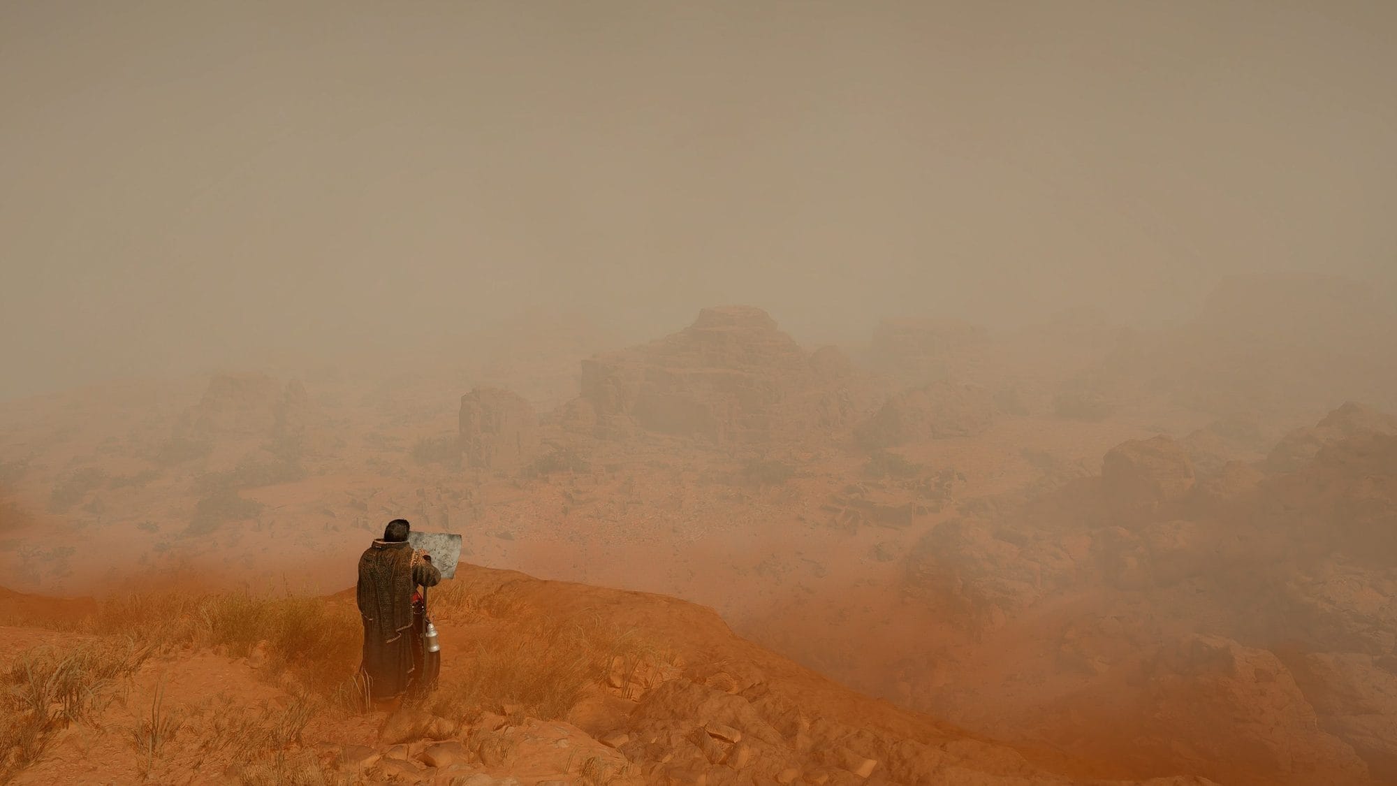 Lone traveler standing on an orange dune looking out over a sandstorm-covered desert