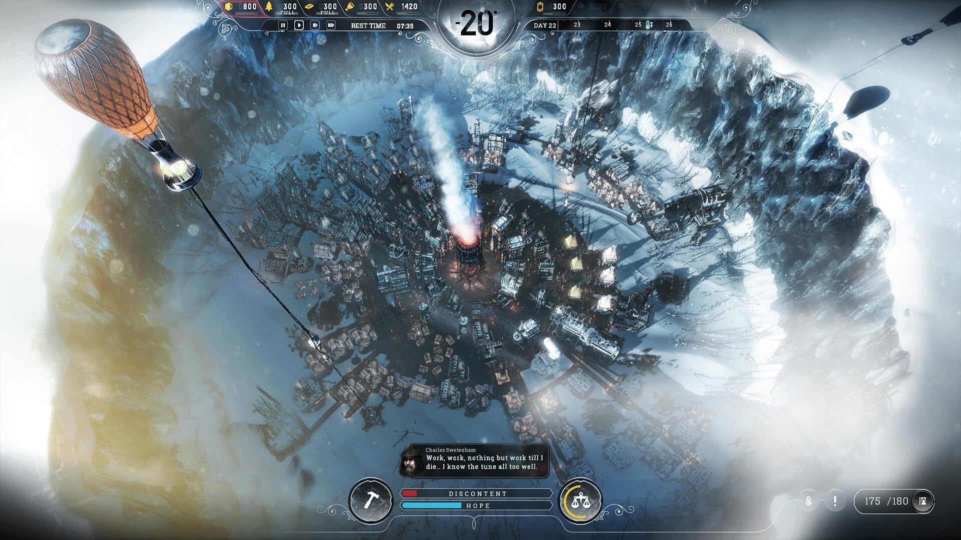 Top-down view of the whole Frostpunk city ringed by ice cliffs with an orange balloon drifting past