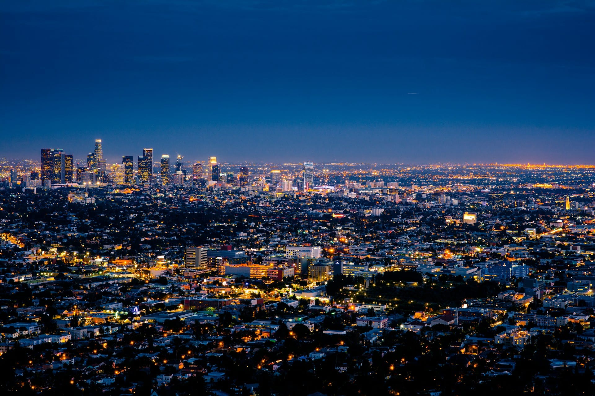 A photograph of Los Angeles at night. The city sparkles with lights and is clearly very densely populated.