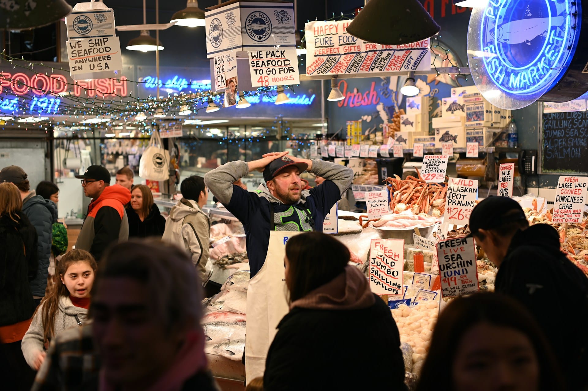 A man stands in the middle of a busy fish market crowd, looking very stressed.