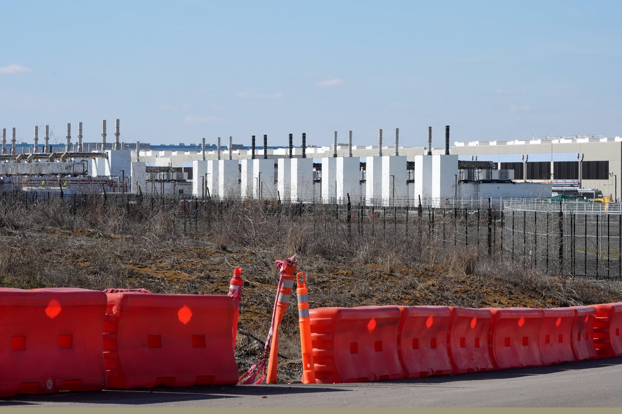 Rows of diesel generators and exhaust stacks are visible from the perimeter of Amazon’s data center campus in Canton, Miss.,