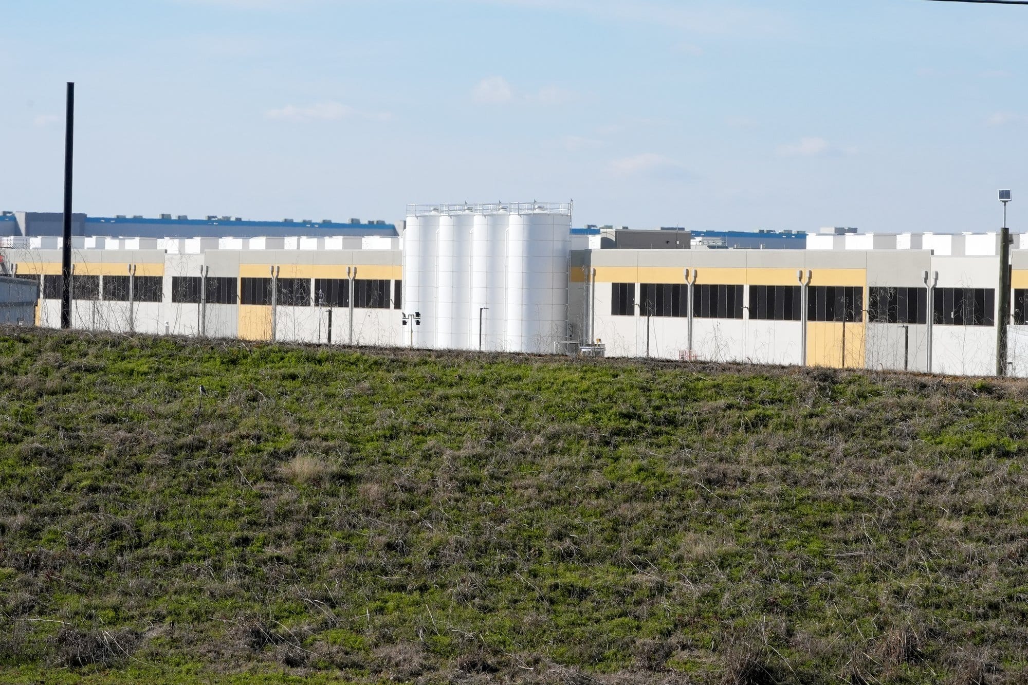 A grassy barrier separates Amazon’s partially completed data center facility in Canton, Miss., from a two-lane highway and a