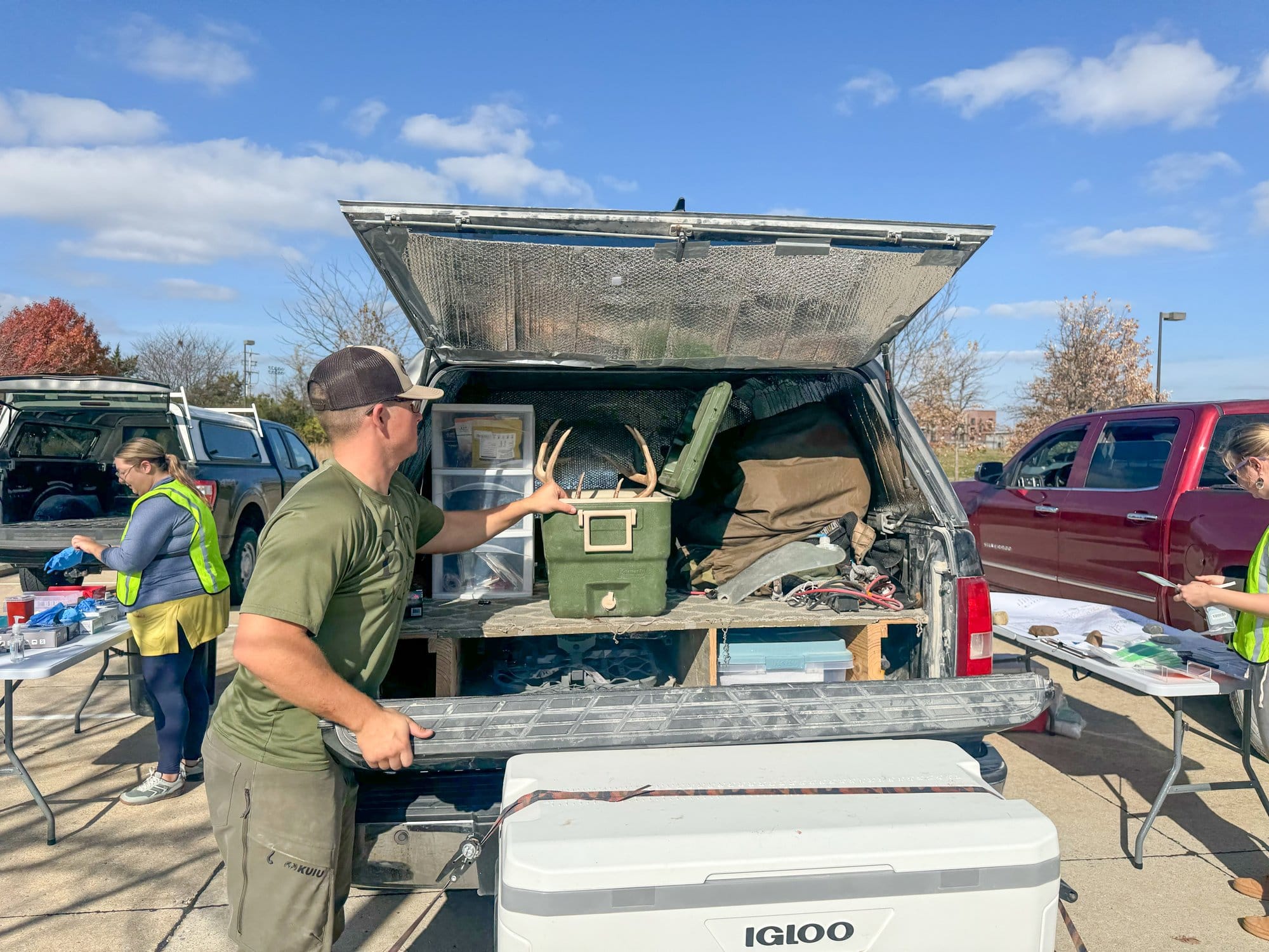 Deer hunter Collin Masters, left, pulls a severed buck head out of his truck to test for chronic wasting disease at a