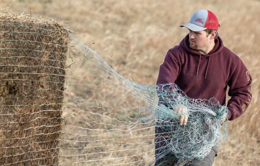 Ben De Boef works on taking the netting off a bale of hay at his family farm in Montezuma, Iowa on Thursday, November 13,