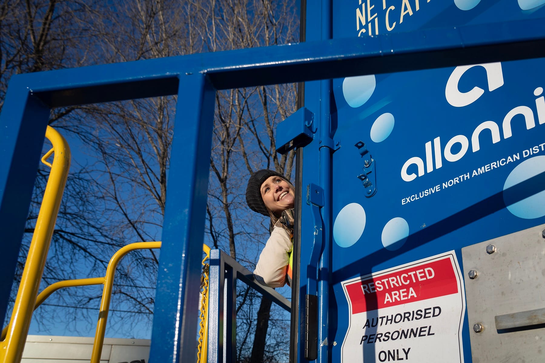 A woman peers out from behind a shipping contianer