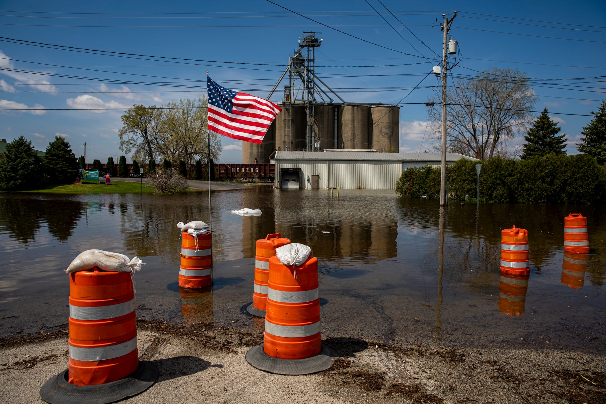 Water floods a parking lot, where hazard cones are scattered