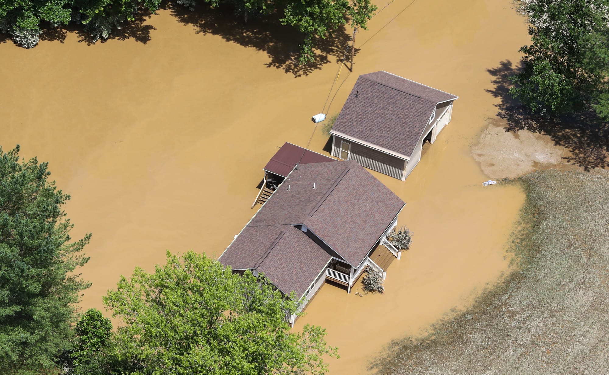 Floodwaters submerge a home and trees