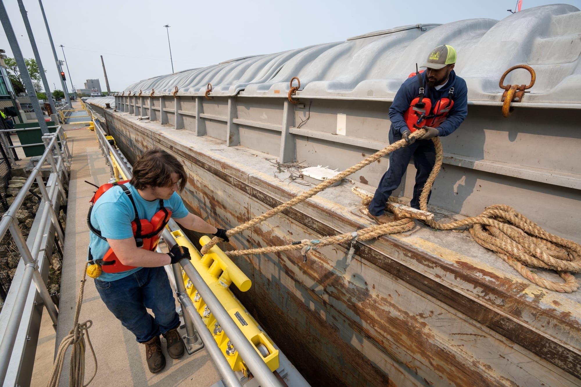 Two men work together to fix a barge to a dock 