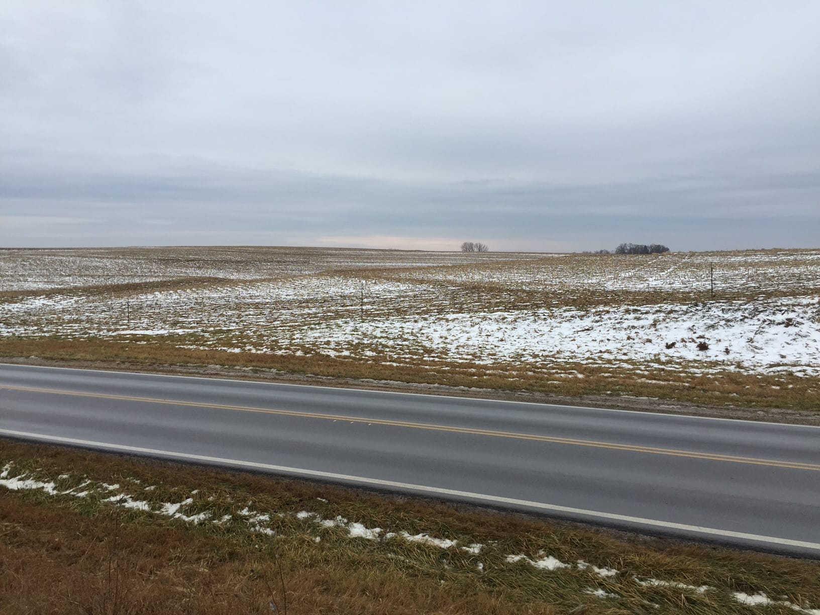 Snow covers fields by a highway
