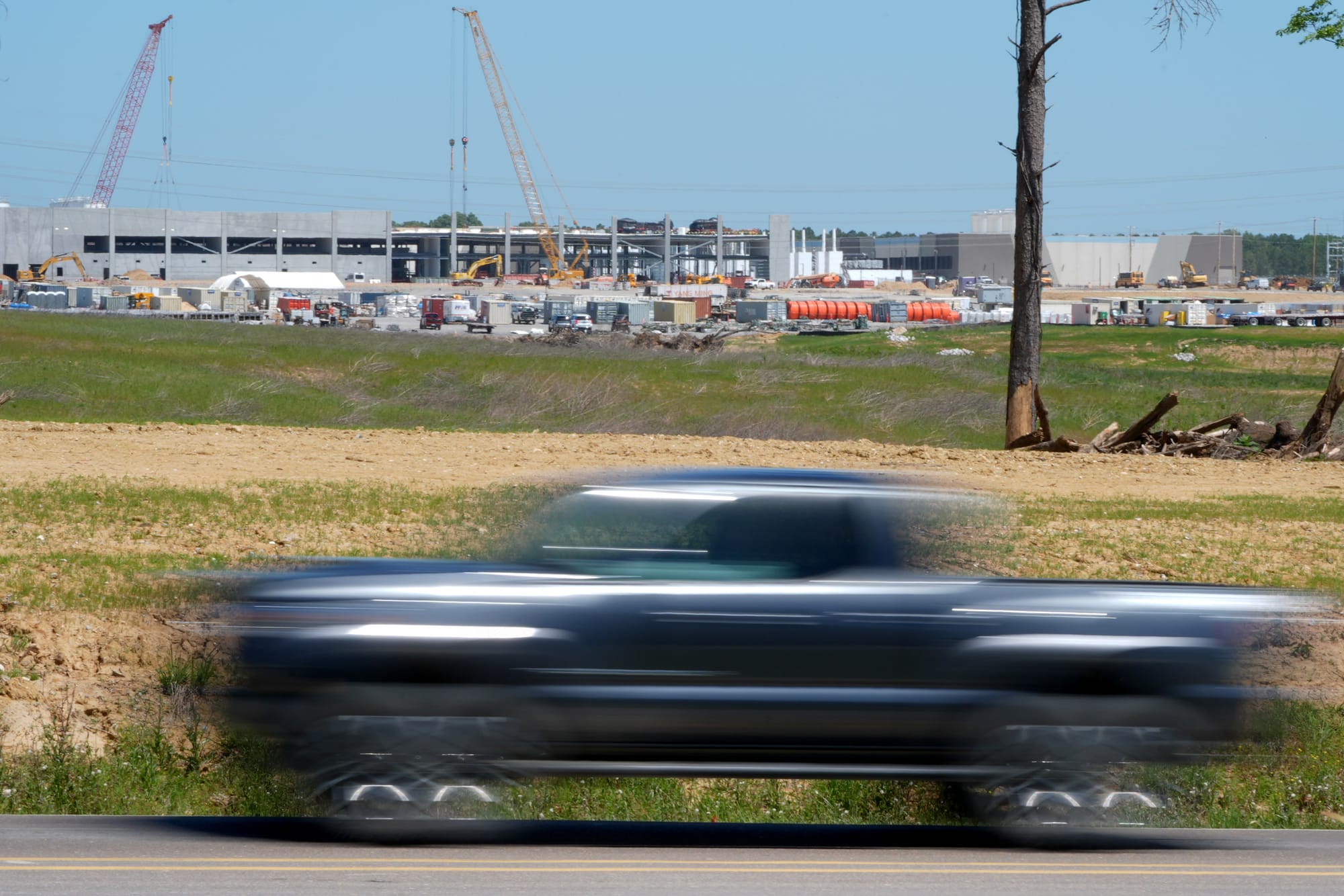 A blurry truck in motion drives past a data center construction site in the background