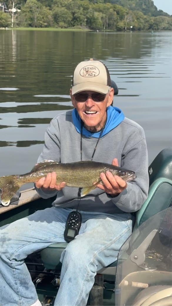 Jerry Boardman holds up a fish in boat.