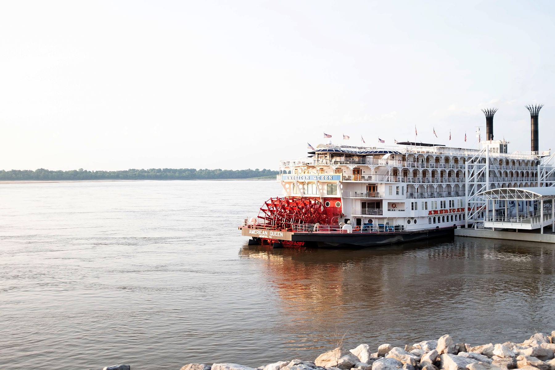 A large red and white riverboat docks on the Mississippi River.
