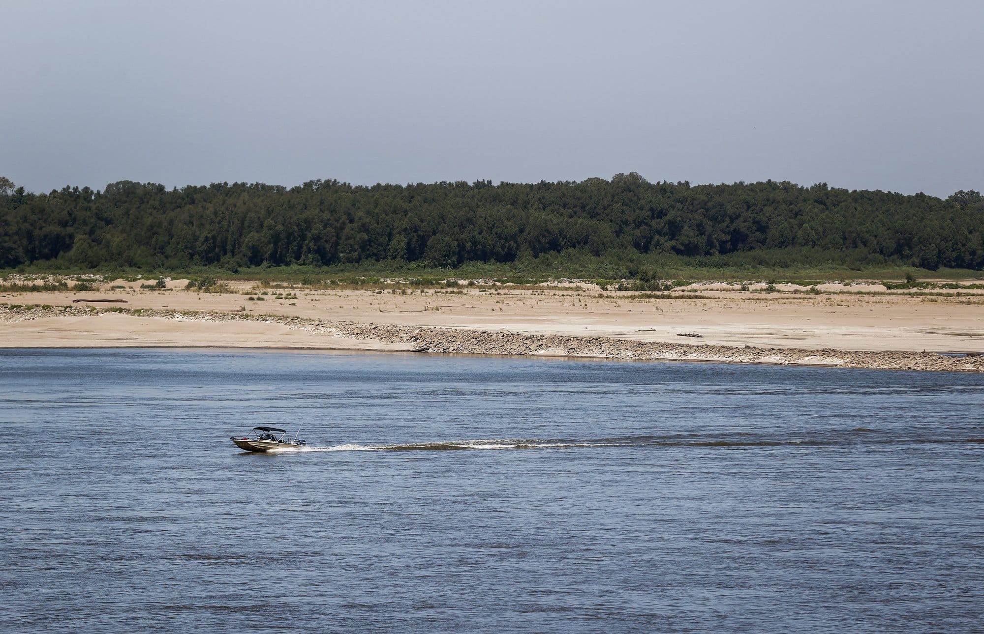 A small boat travels along the Mississippi River near Memphis, Tennessee, as exposed sandbars along the riverbank show unusually low water levels.