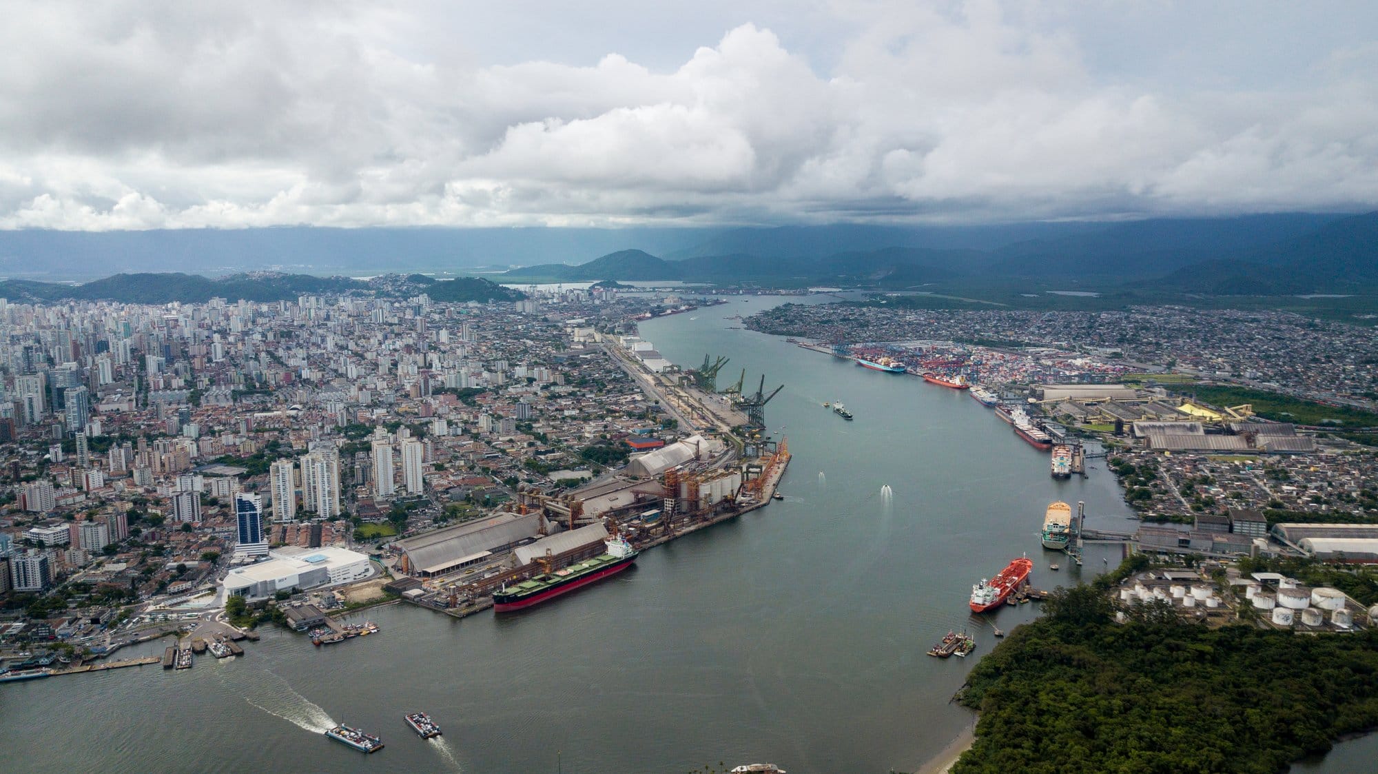 Cargo ships are docked on the edges of a city's river