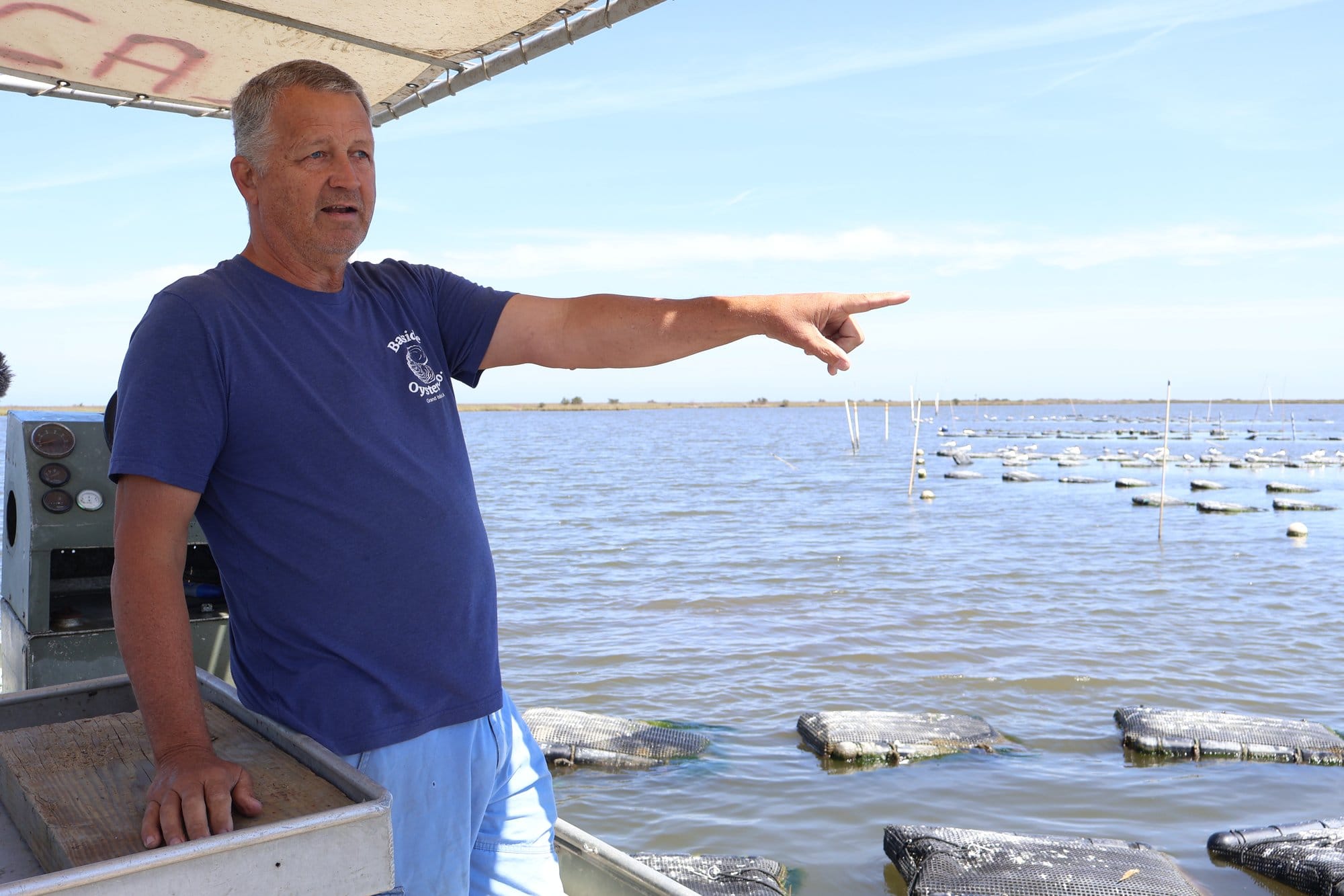 Curole stands and points as he describes his day running a small off-bottom oyster business in Grand Isle, Louisiana.
