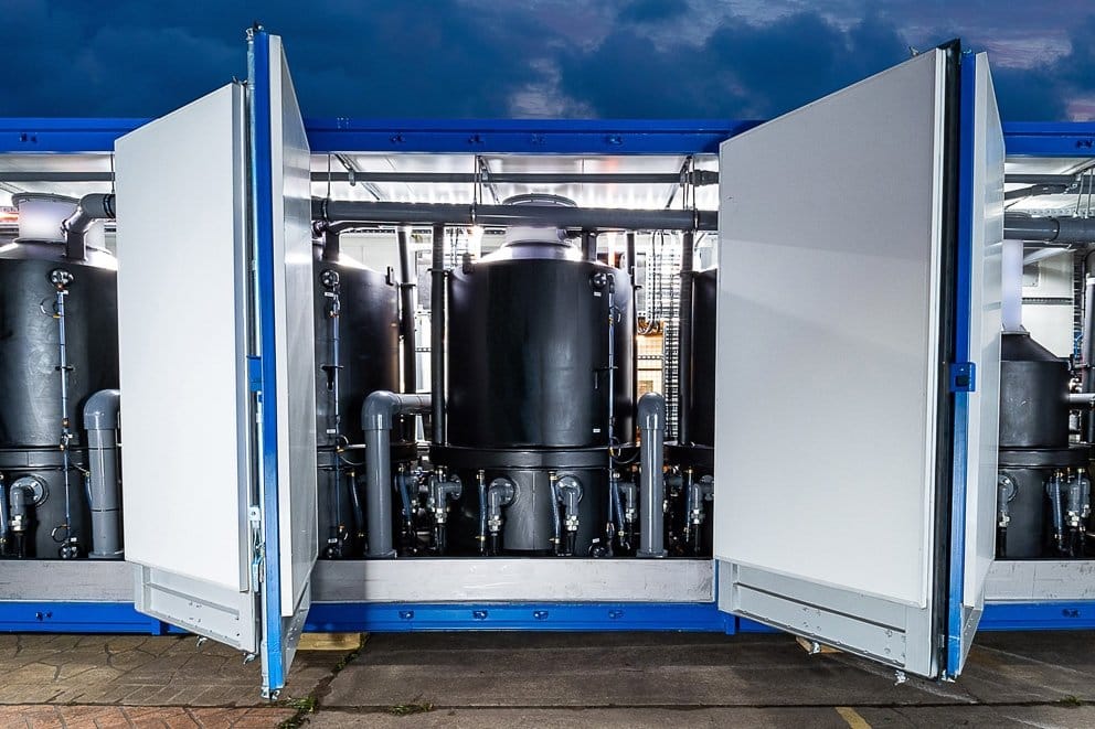 Large black tanks and pipes inside a containerized PFAS water filtration system being tested in Minnesota.