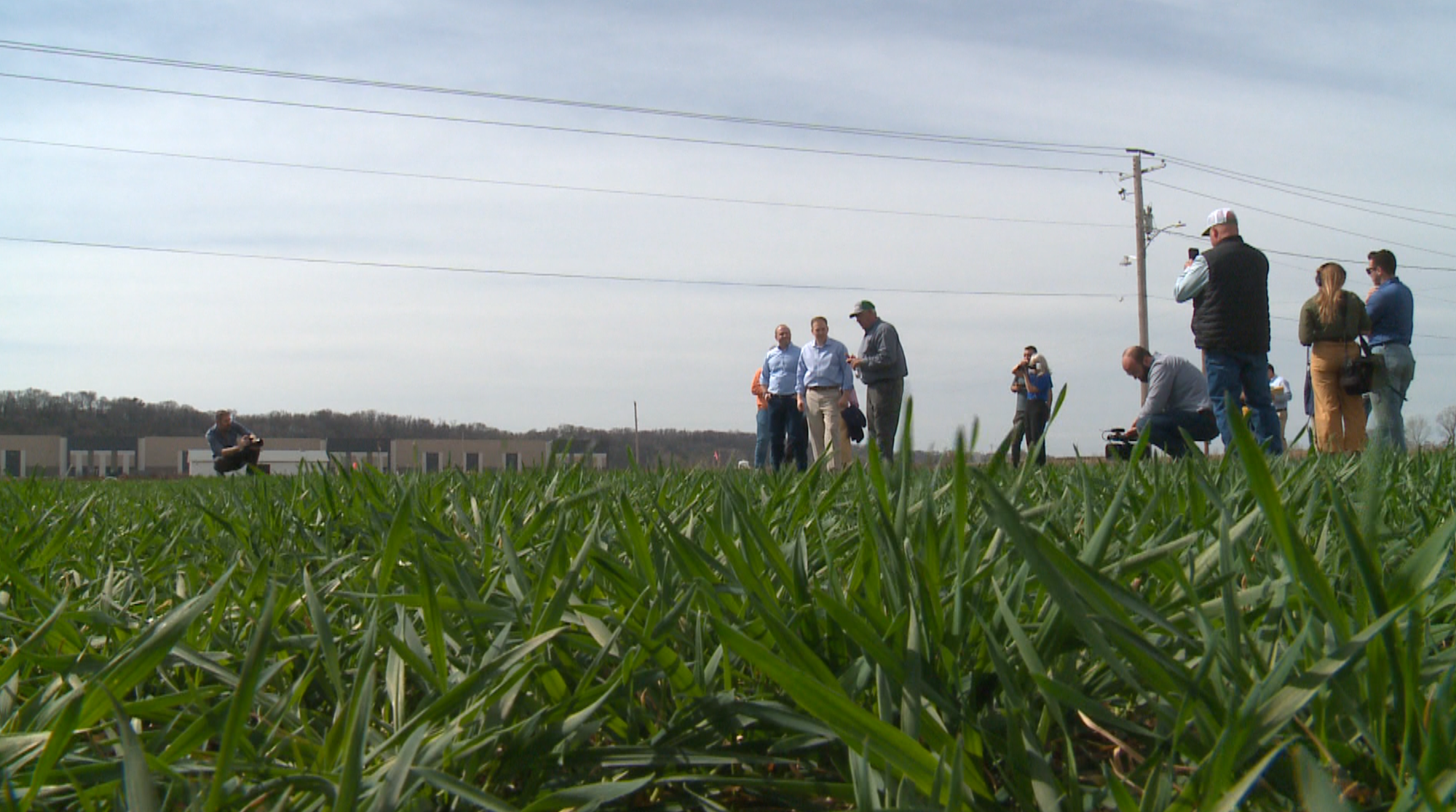 A group of people, including EPA administrator Lee Zeldin, stand on farmland discussing wetland regulation changes under the Trump administration.