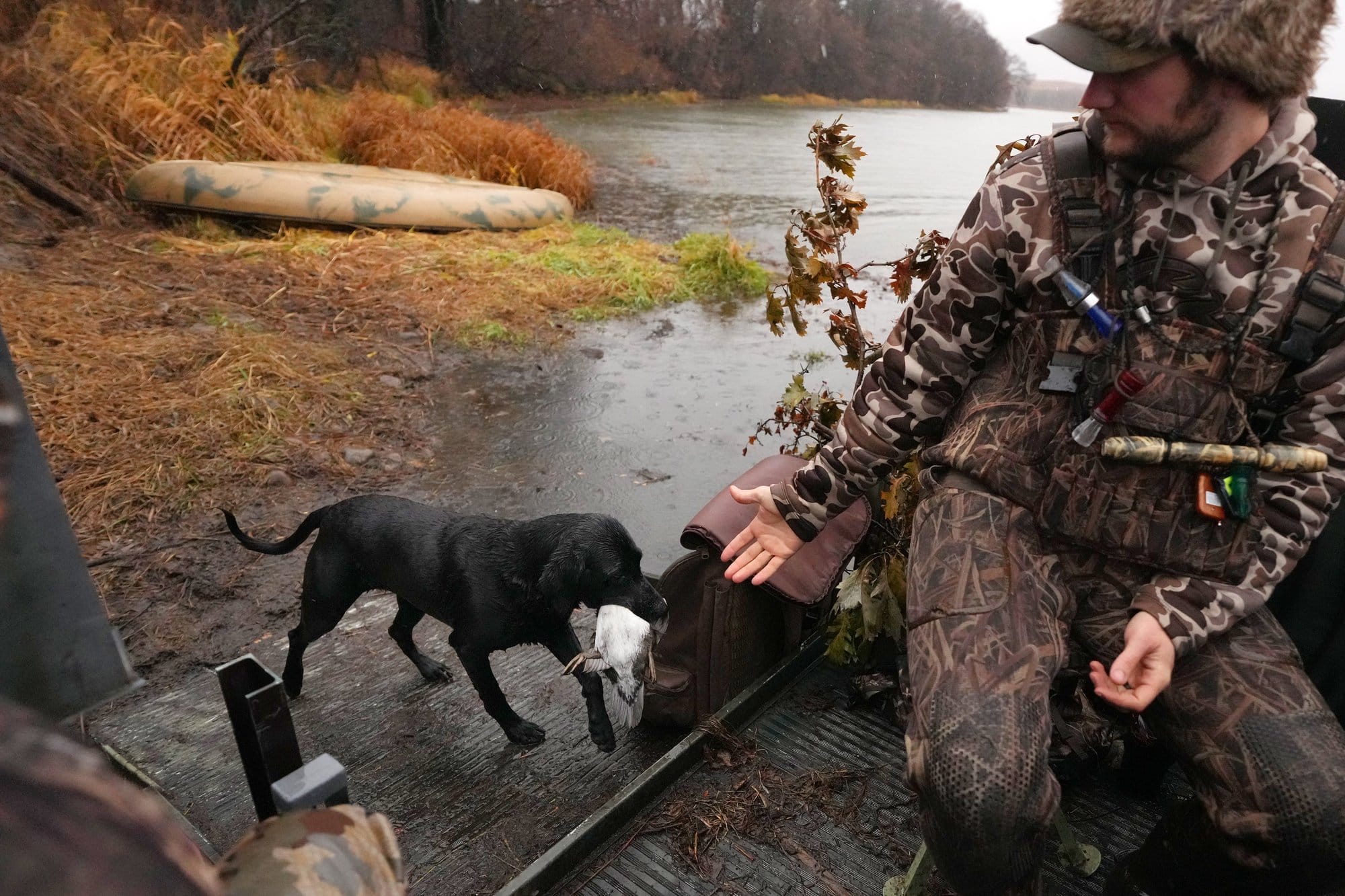 Jordan Lillemon waits as his black Labrador retriever, Kettle, returns with a bird.