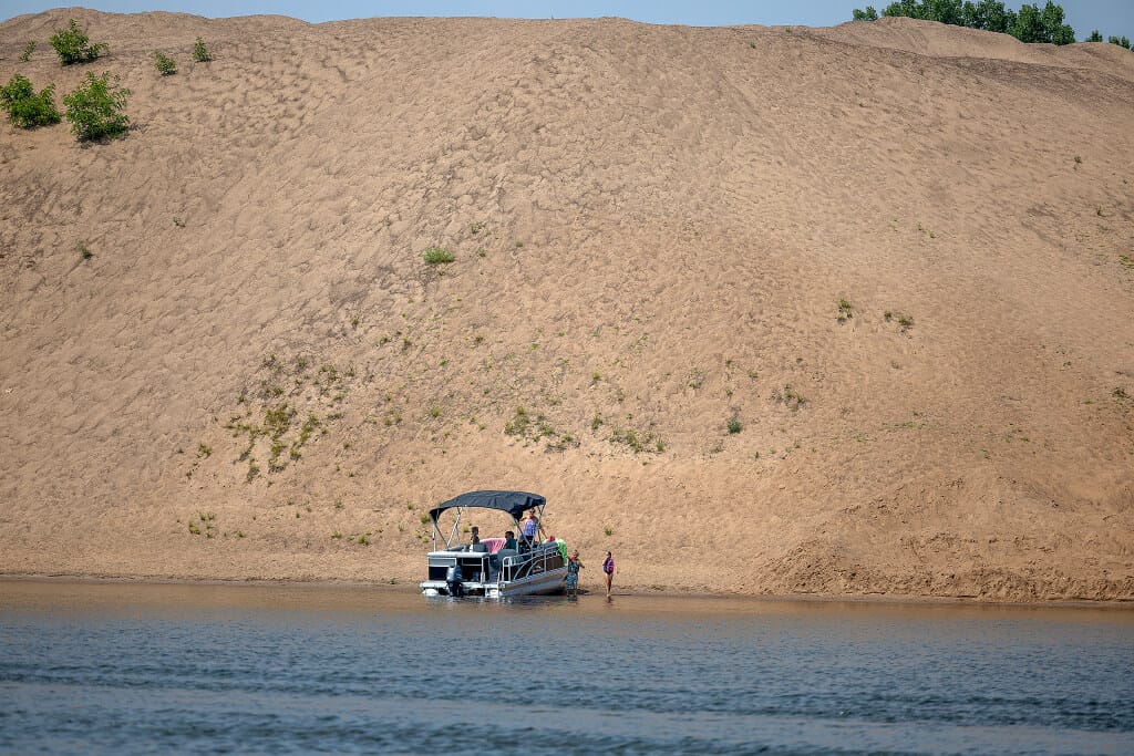 A boat docks on a sand island in the Mississippi River