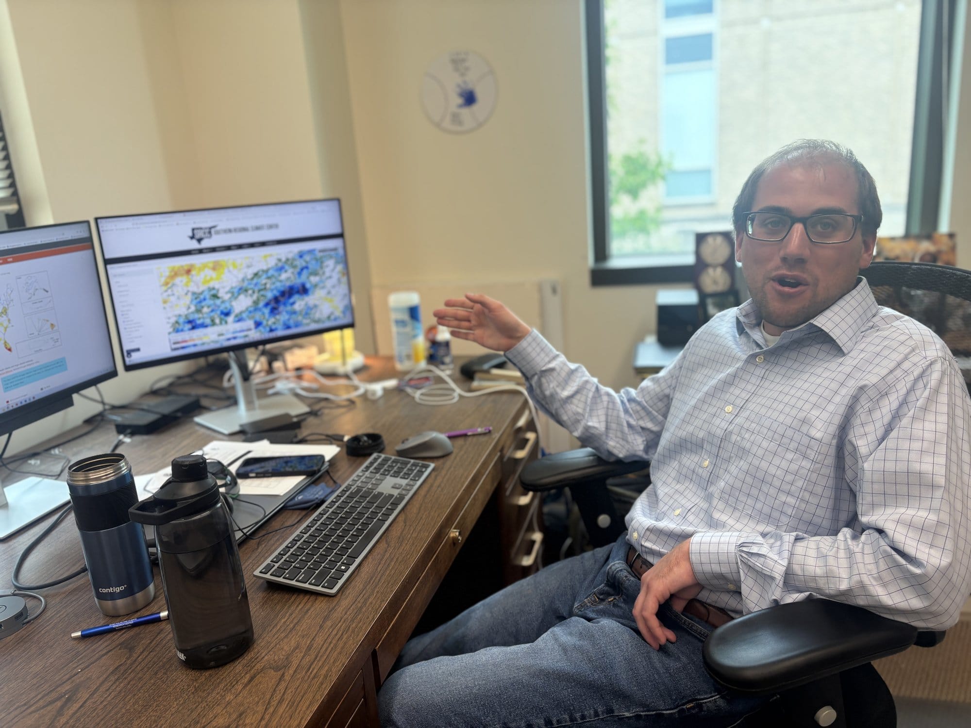 Missouri State Climatologist Zack Leasor gestures toward computer screens displaying weather and drought reports in his Columbia office.