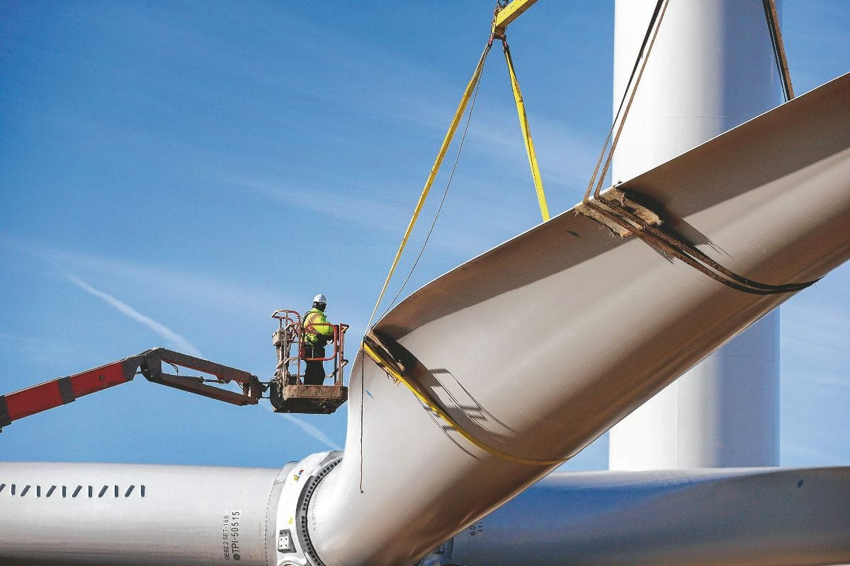 A worker installs a wind turbine blade