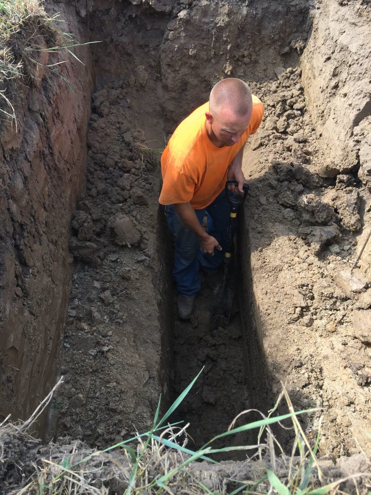 Harold Beach’s son, Chris Beach, sets up a trench before laying drainage tile.