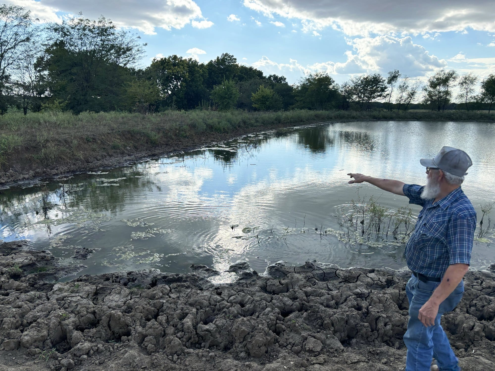 Wilburn Harris pointed at the low water level of a pond on his farm in Drexel, Mo.