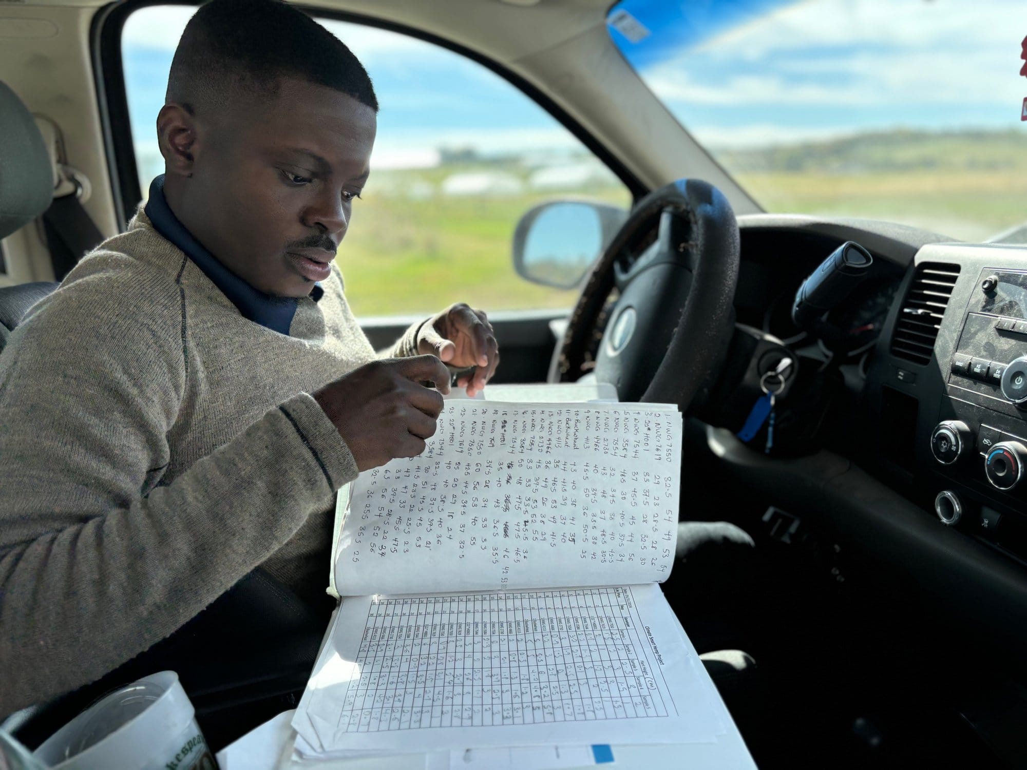 A man sits in a truck and looks through papers with data recordings