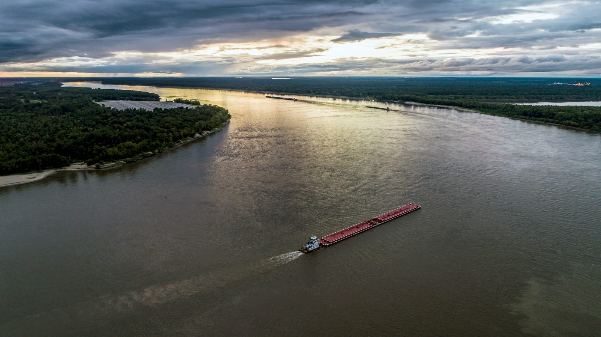 a barge pulls cargo down a river