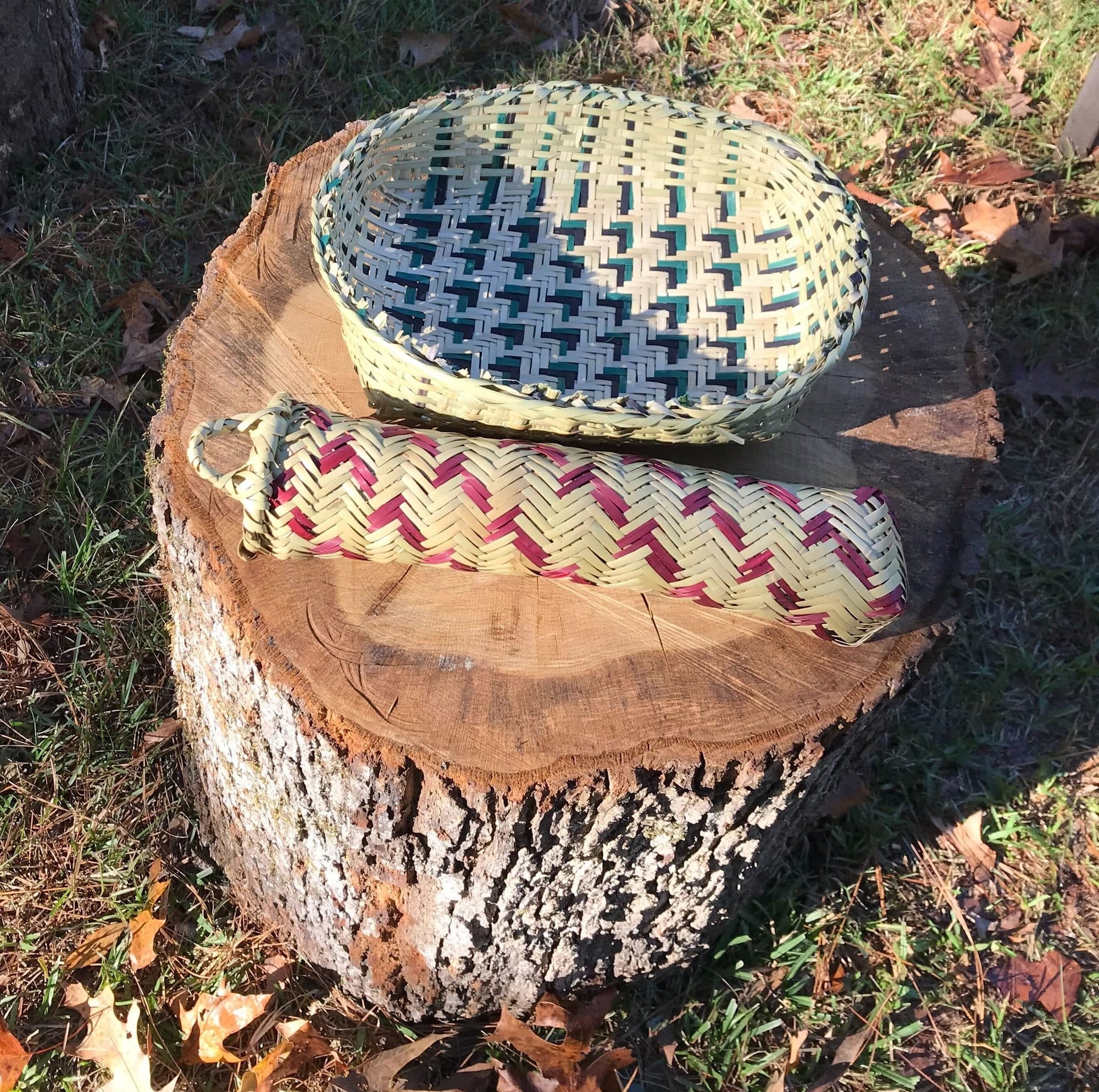 Two river cane baskets woven in traditional Choctaw patterns rest on a tree stump.