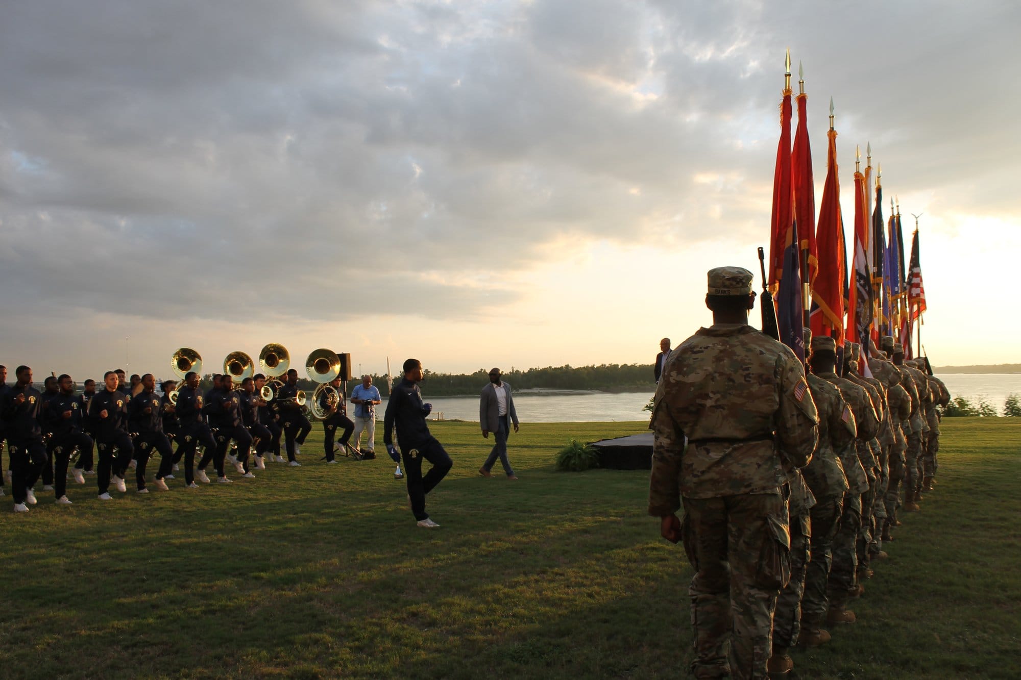 The Southern University ROTC Color Guard march beside a university marching band during an outdoor event along the Mississippi River.