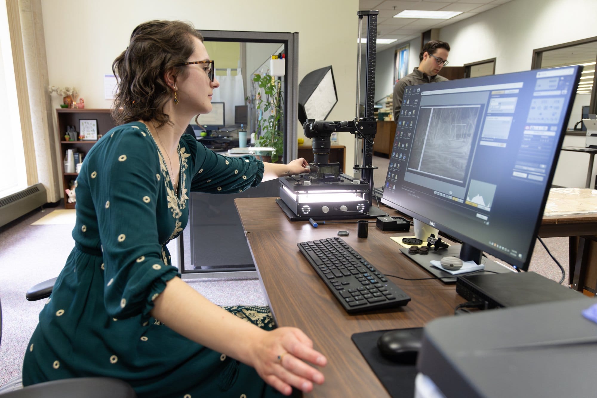 A woman works with a digitization tool in front of a laptop screen